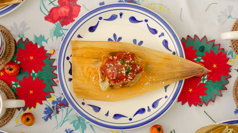 tamale à la sauce rouge affiché sur une nappe de fleurs de Noël