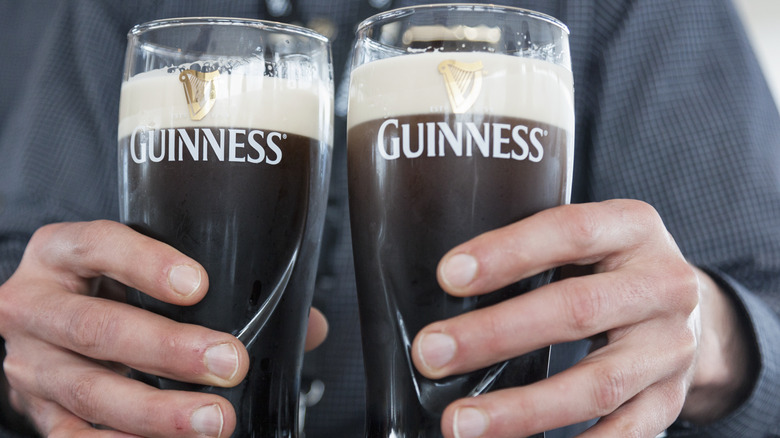 Une personne tenant deux pintes de bière Guinness