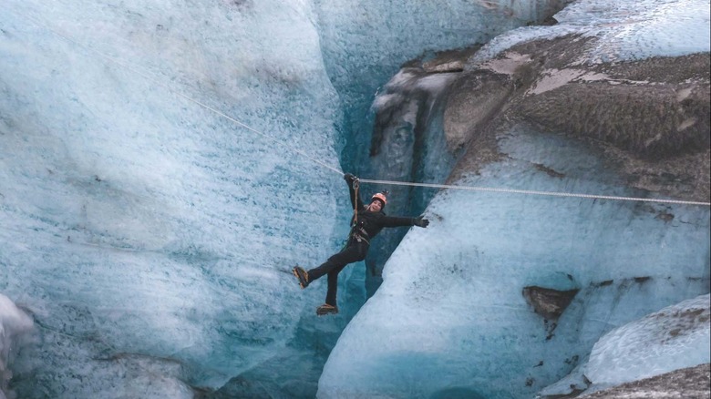 Une femme sourit en survolant une tyrolienne glacier