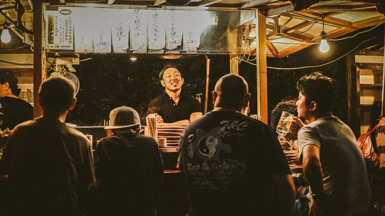 Le propriétaire de l'atelier s'exprime avec des clients dans un Fukuoka Yatai