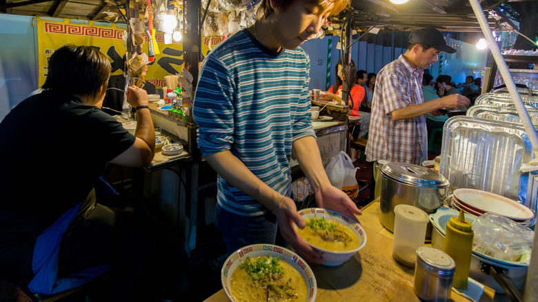 Un vendeur de magasin préparant des bols de ramen dans un yatai