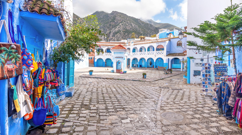 Une rue bordé d'artisanat et de vêtements menant à une place à Chefchaouen, Maroc