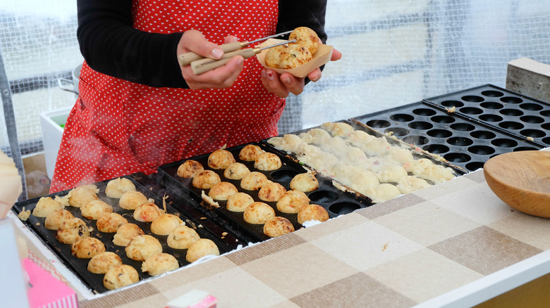 Personne qui fabrique et tient Takoyaki au marché du matin de Takayama au Japon