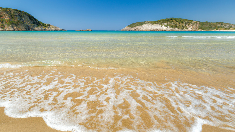 De petites vagues s'écrasent sur le rivage par une journée ensoleillée à Voidokilia Beach