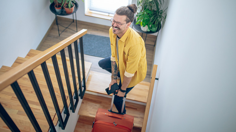 Jeune transportant ses lourds bagages dans les escaliers
