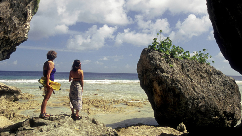 Deux personnes se préparent à faire de la plongée dans le rivage rocheux de Niue