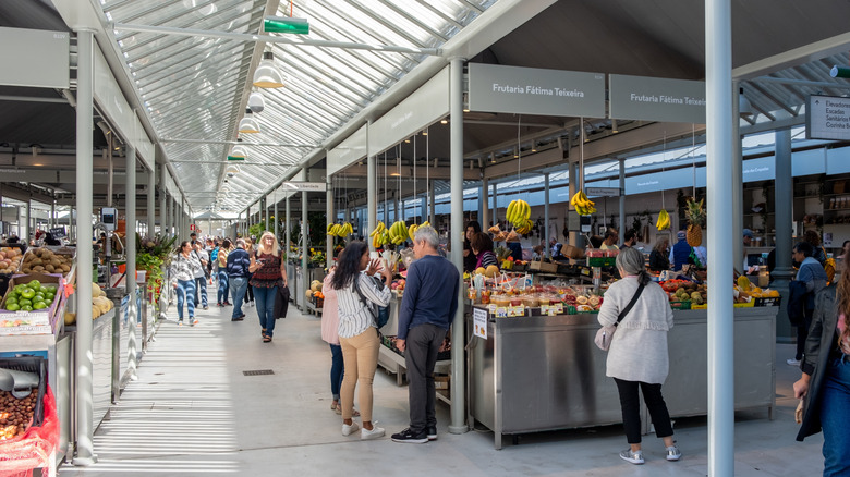 Les acheteurs regardent les produits à l'intérieur moderne du marché de Bolhão à Porto, au Portugal,