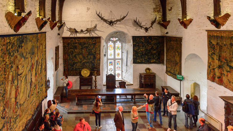 La grande salle du château de Bunratty avec des touristes prenant des photos
