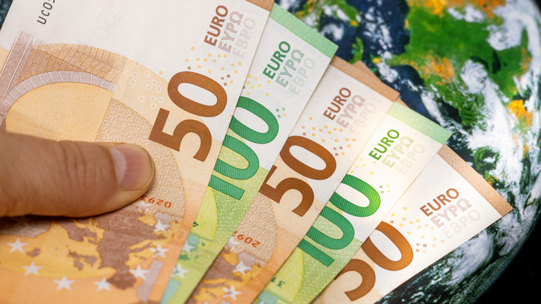 Hand détient les euros sur la carte du monde