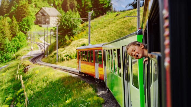 Petite fille sort la tête du train dans des paysages alpins en Suisse