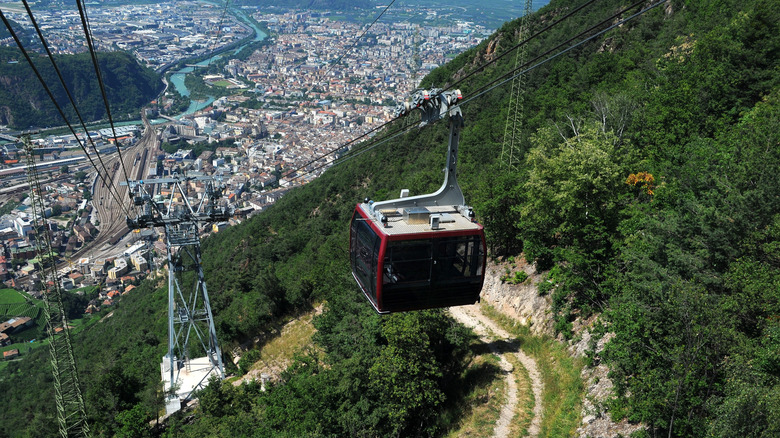 Un téléphérique rouge contre une vue de la ville de Bolzano ci-dessous