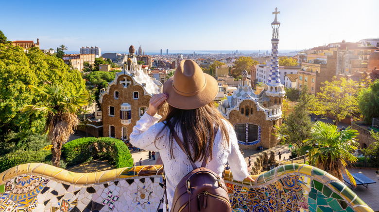 Femme avec un chapeau et un sac à dos regardant la vue sur le parc à Barcelone