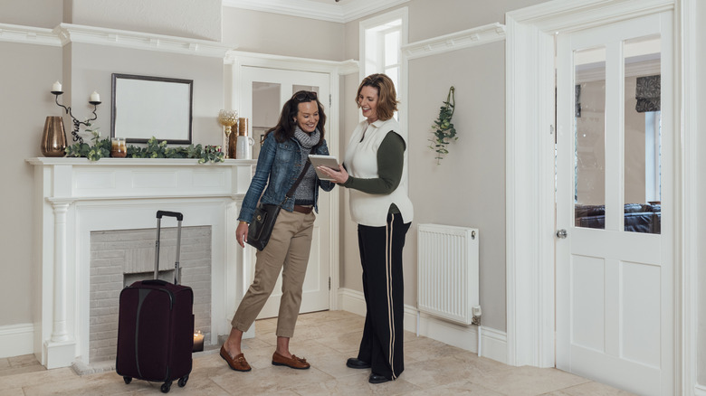 Une femme avec une valise rencontrant un animateur de location avec une tablette