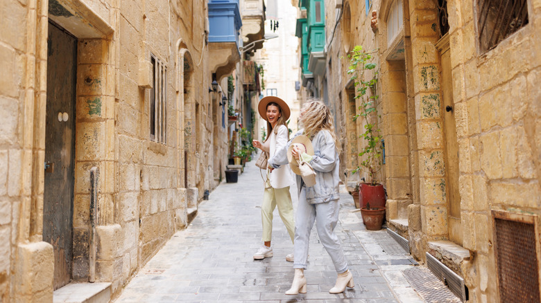 Deux femmes se tenant la main et riant dans les rues de Valette, Malte