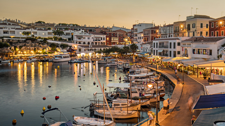 Coucher de soleil derrière un port de menorca illuminé rempli de bateaux