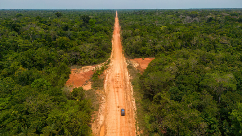 Une voiture conduisant sur un chemin de terre à travers l'Amazonie brésilienne pendant la saison sèche