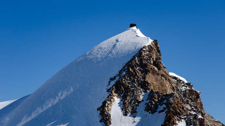 Petite cabane de montagne perchée au sommet d'un sommet de la montagne enneigée