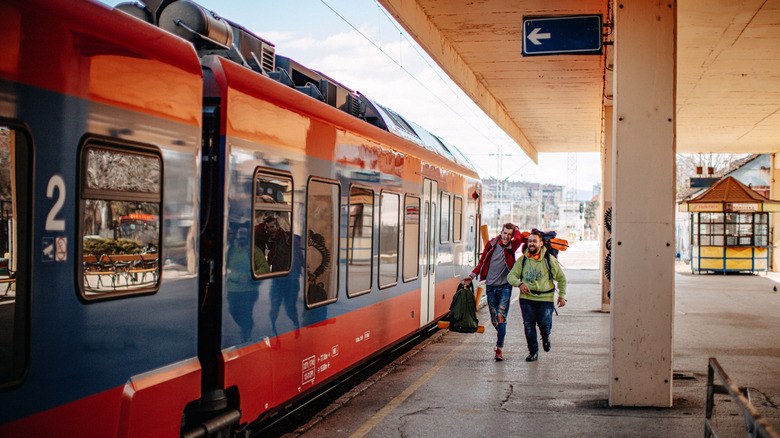 Deux hommes avec des sacs à dos sur le dos coulant vers le train sur la plate-forme