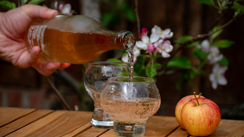 Serveur versant un verre de cidre de Normandie en deux verres.