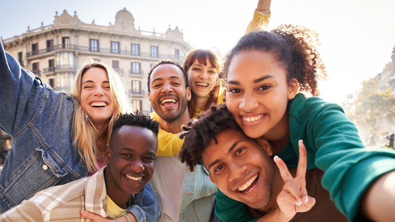 Des amis souriant et posant avec un bâtiment européen