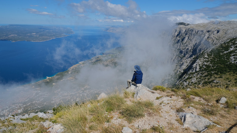 Un randonneur assis sur un rebord sur l'île de Brac, Croatie