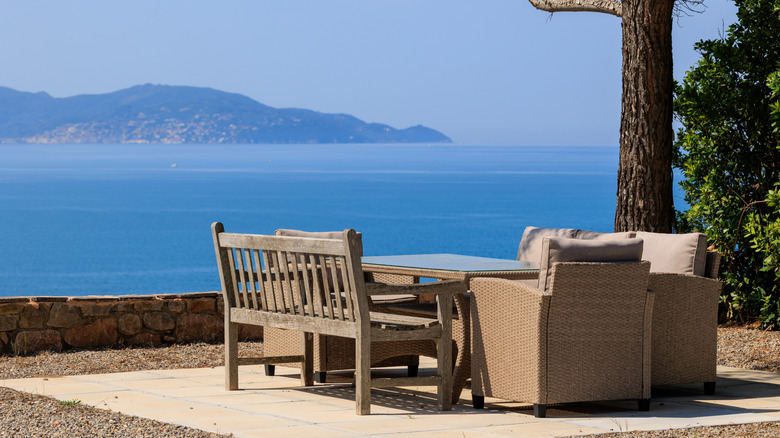 Un coin salon de jardin avec des détenteurs surplombant la mer bleue et les montagnes au loin.