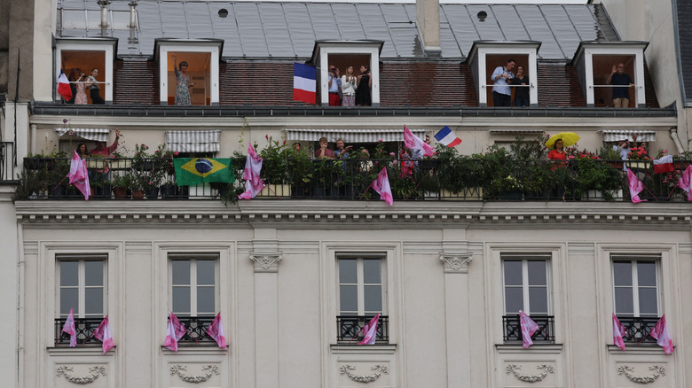 Personnes célébrant l'événement sportif dans les fenêtres d'appartements parisiens