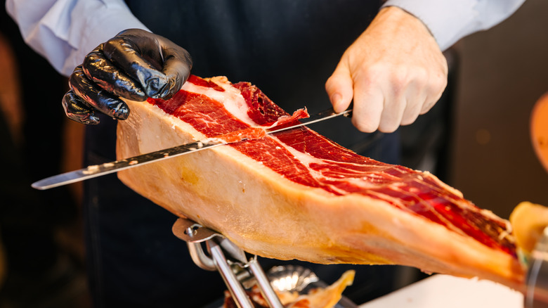 Une personne tranchant un morceau de jamon d'Espagne