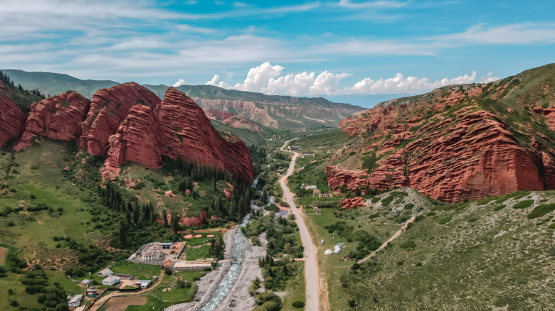 Route et rivière à travers de grandes rochers rouges au Kirghizistan
