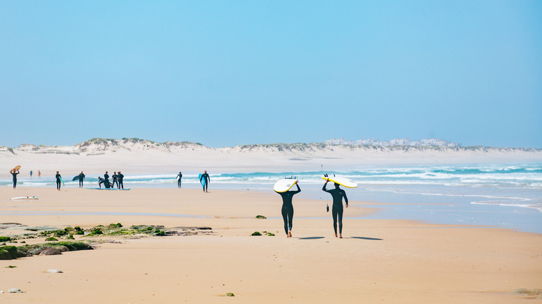Surfers avec planches de surf marchant le long de l'une des plages de Baleal