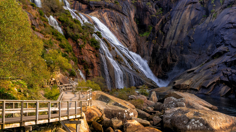 Une cascade devant une promenade en bois dans un canyon
