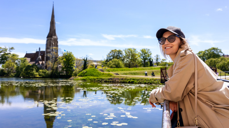 Femme souriant devant Kastellet Citadel Park contre l'église St. Alban's à Churchill Park, Copenhague, Danemark