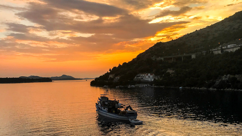 Un bateau sur l'eau par la plage de Sveti Jakov en Croatie au coucher du soleil