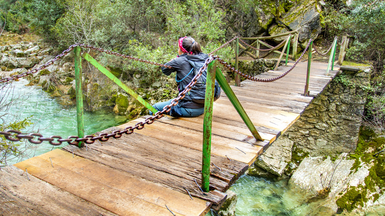 Une fille assise un pont au Río Barosa, en Espagne