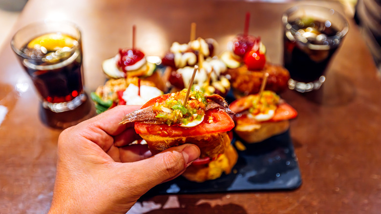 Une personne tenant des tapas devant une assiette