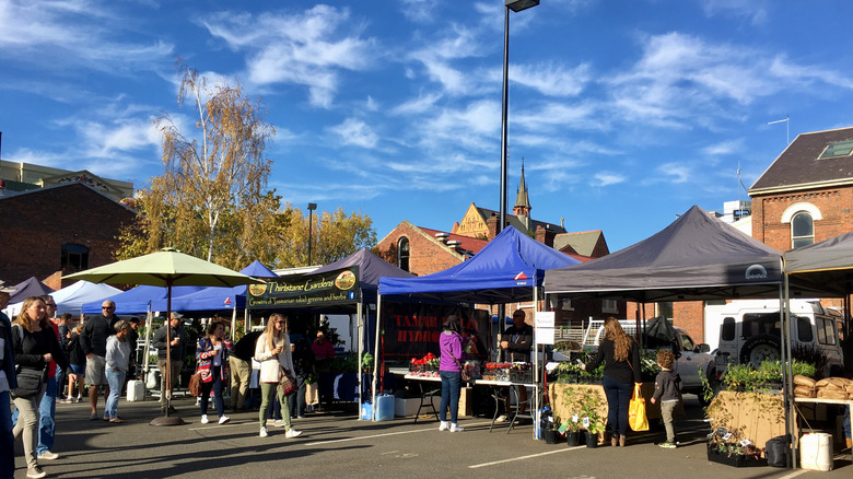 Les gens se promènent dans des étals de marché par une journée ensoleillée