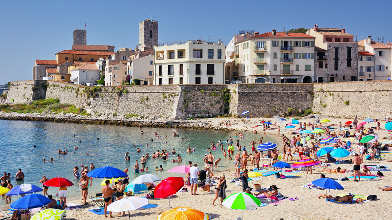 Une plage animée dans les antibes par une journée ensoleillée avec des parapluies colorés