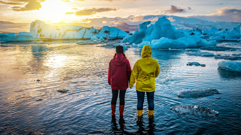 Deux personnes regardent le soleil se coucher sur un lagon glacier en Islande