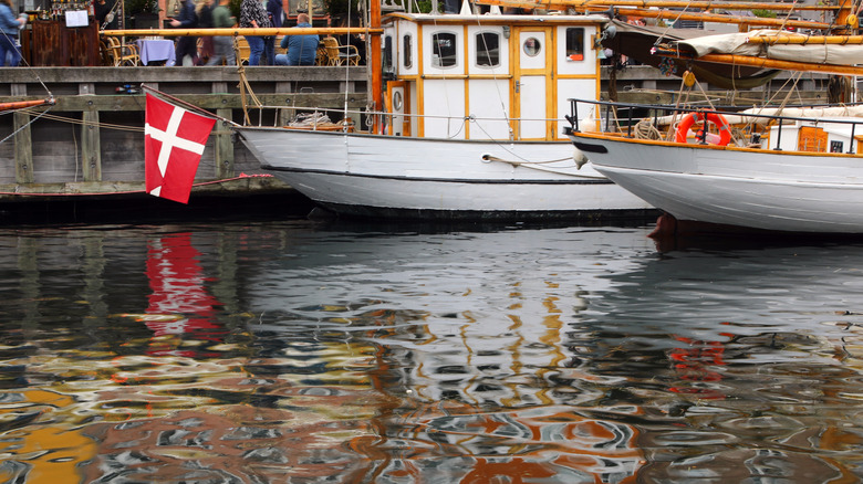 Les bateaux historiques, un avec un drapeau danois, se reflètent dans l'un des canaux de Copenhague