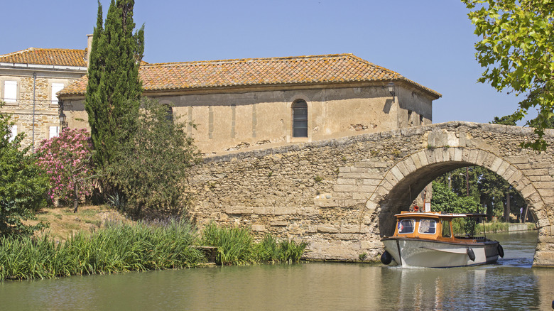 Un bateau passant sous un pont en pierre sur le canal du midi à Le Somail, France