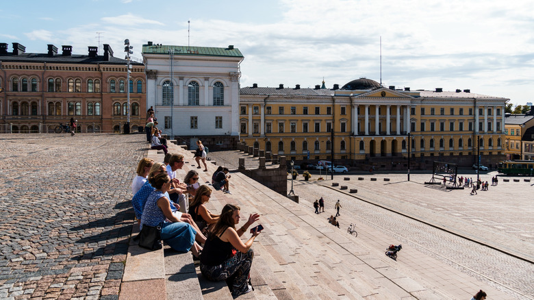 Un groupe de personnes assises sur les marches d'une place d'Helsinki en Finlande