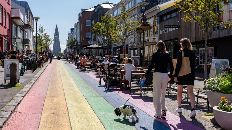 Des femmes promenant un chien dans une rue arc-en-ciel à Reykjavik, en Islande, se terminant à la cathédrale