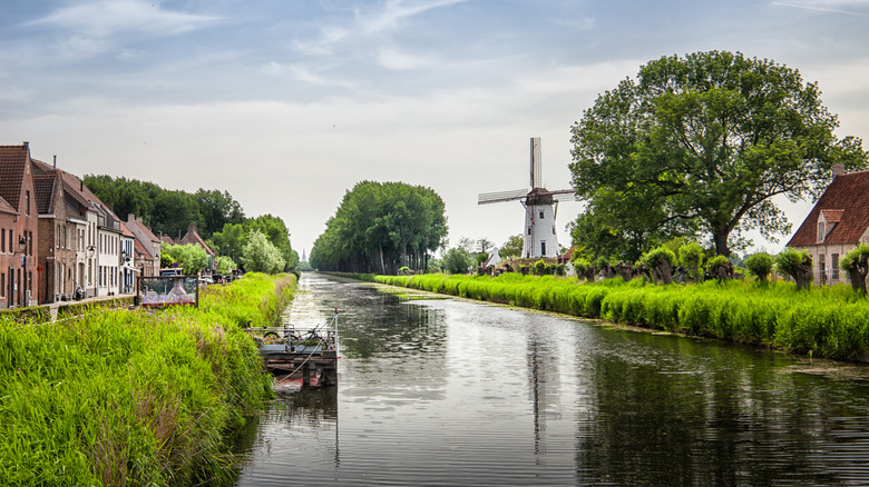 Canal près de Damme, en Belgique, bordé d'un moulin à vent traditionnel et des bâtiments en brique historique
