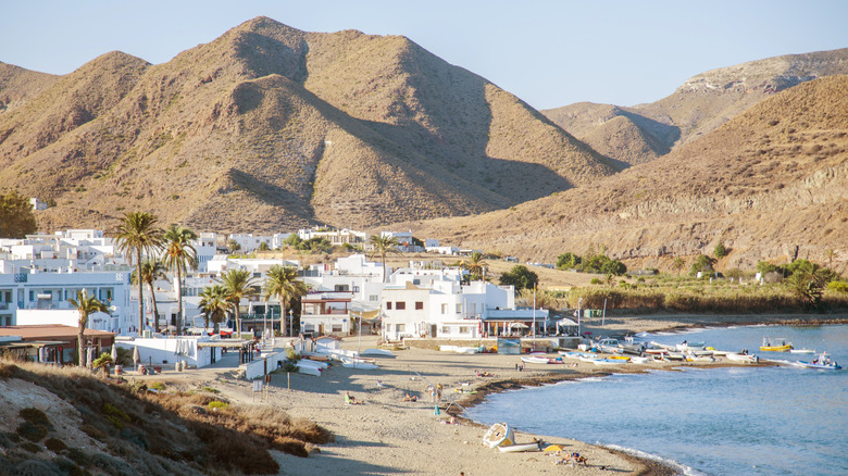 Une ville blanche à la chaux repose au bord de la mer sous une chaîne de montagnes volcaniques près de l'Espagne Cabo de Gata Natural Park