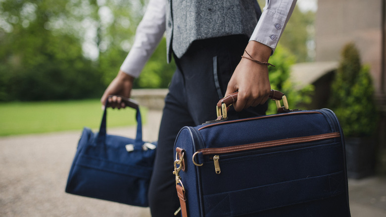Image recadrée d'un portier en uniforme transportant deux bagages