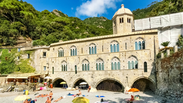 Les gens brontent sur une plage de galets à San Fruttuoso, Camogli