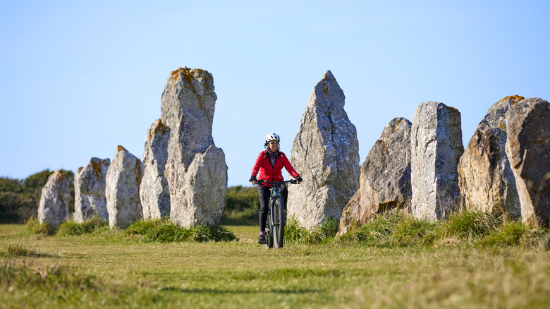 Femme à vélo entre les pierres mégalithiques de Carnac