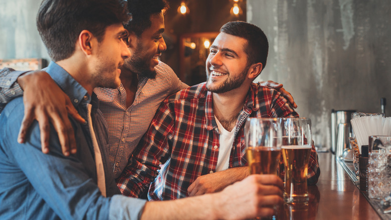 Trois amis masculins buvant Guinness dans un pub.