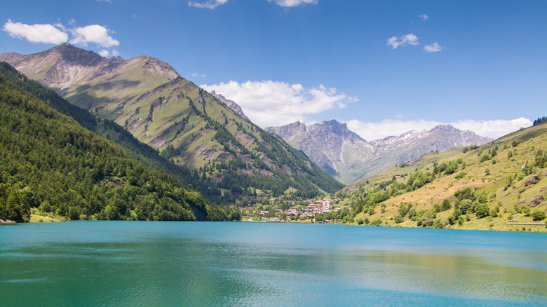Eau bleue dans le lac avec village et montagnes derrière
