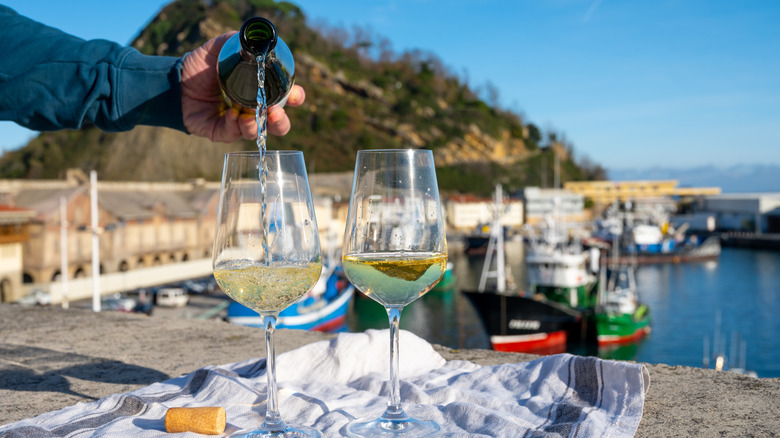 Verser le txakoli avec le port d'Etaria en arrière-plan